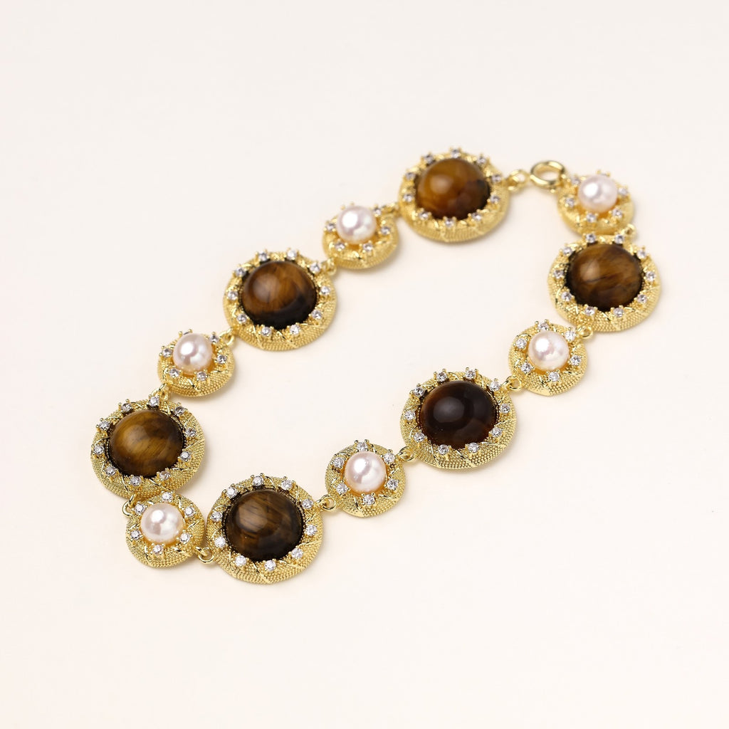 Ornate gold-plated bracelet with alternating brown tiger's eye stones and white freshwater pearls in crystal-accented settings