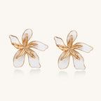 Large floral stud earrings with gold-plated brass petals and white enamel centers on neutral background
